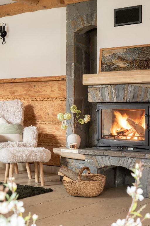 a living room with a fireplace and two chairs at Willa Podhalanka Jacuzzi & sauna - drewniany dom dla 20 osób in Biały Dunajec