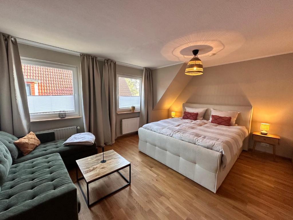 a bedroom with a large bed and a couch at Sky & Sand - Endless Sea I Hochwertige, stilvolle Wohnungen, Strandnah, Boxspringbett, mit Garten in Sankt Peter-Ording