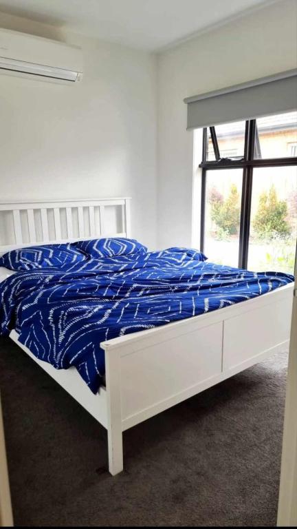 a white bed with a blue comforter in a bedroom at Cozy Room with Private Bathroom in Wheelers Hill