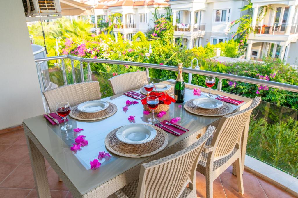einen Tisch mit Tellern und Weingläsern auf dem Balkon in der Unterkunft Sunset Beach Club Aqualettings Poseidon 7 in Fethiye