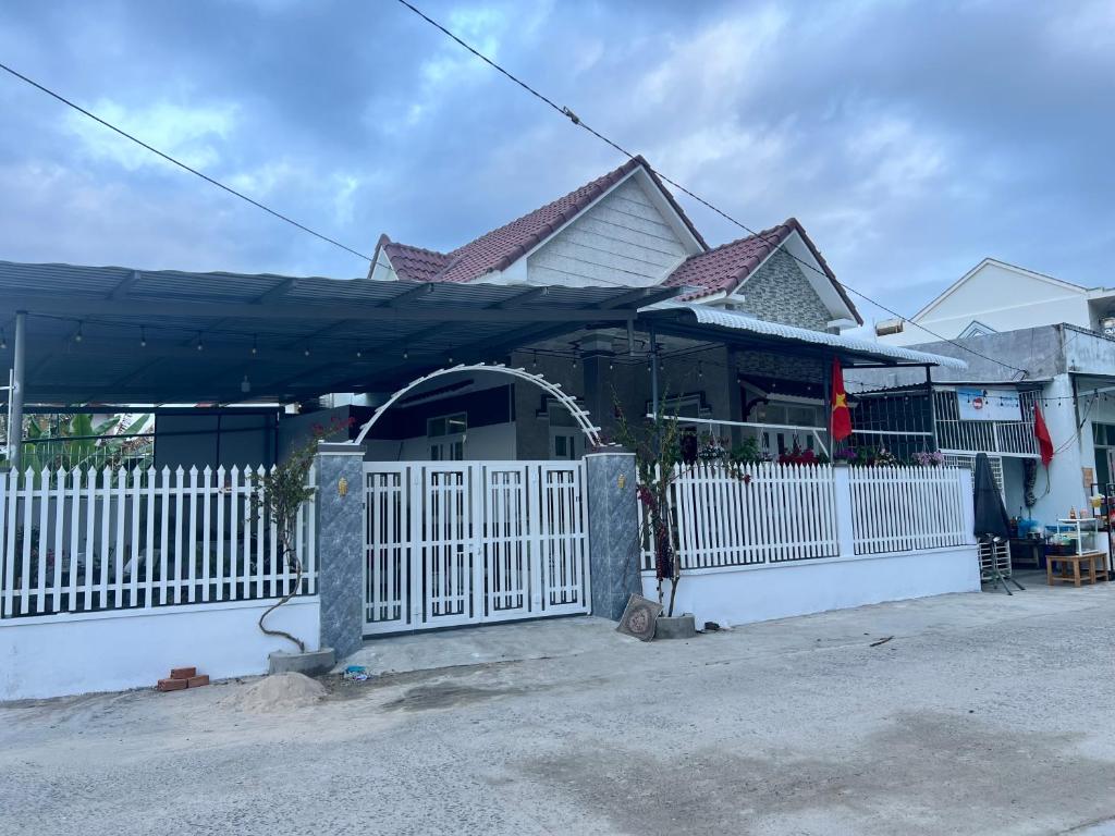 une maison avec un portail blanc et une clôture dans l'établissement Ryo Homestay Dốc Lết, à Ba Ha