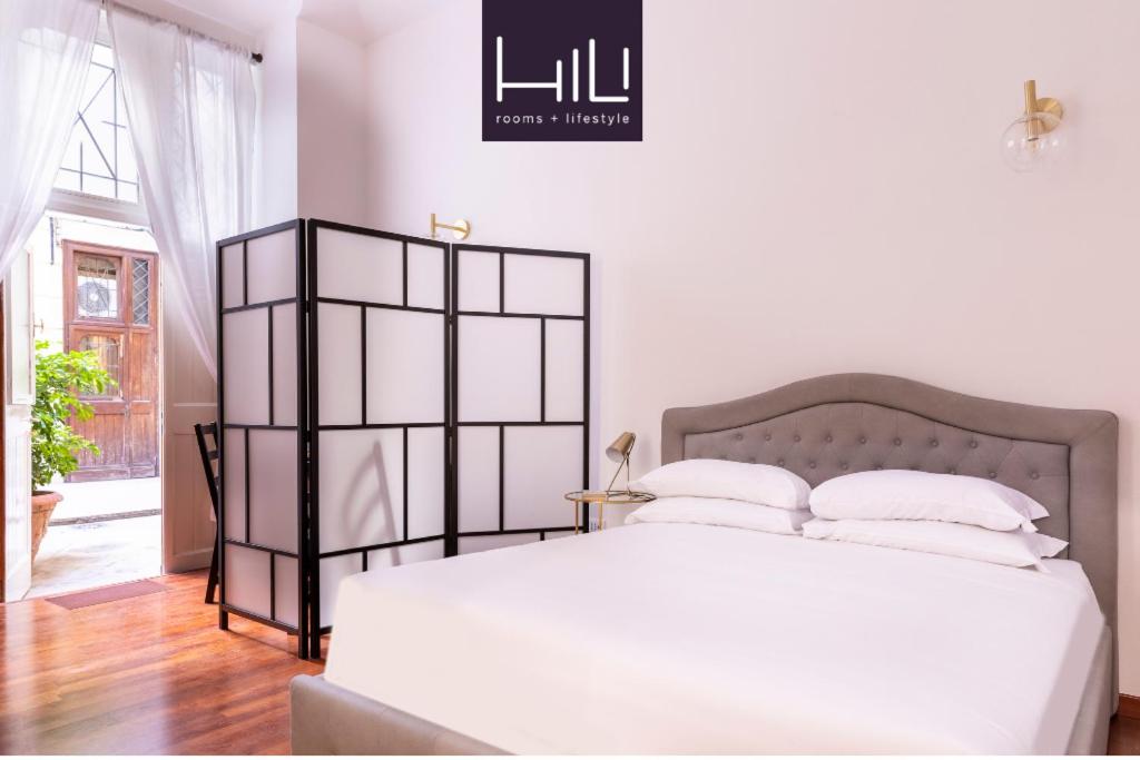 Un dormitorio con una gran cama blanca con almohadas blancas. en Casa Salandra by Hili, en Roma