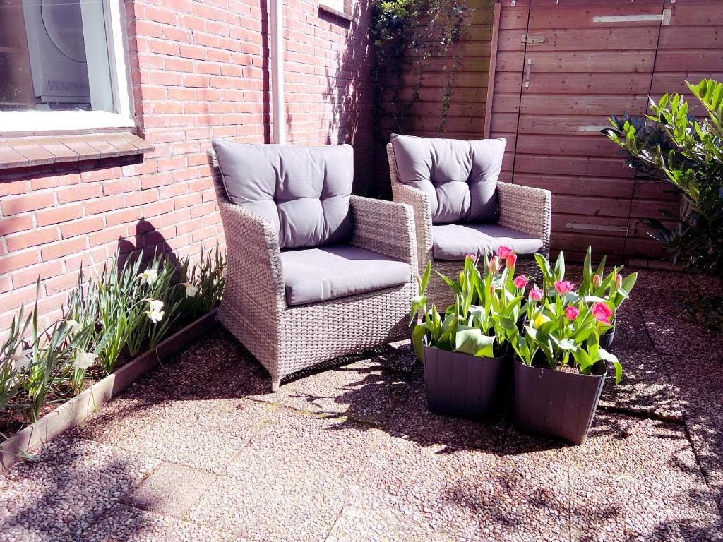 - 2 chaises en osier et des fleurs sur la terrasse dans l'établissement DomCity Apt Near Amsterdam Bikes Included One mile to City Centre, à Utrecht