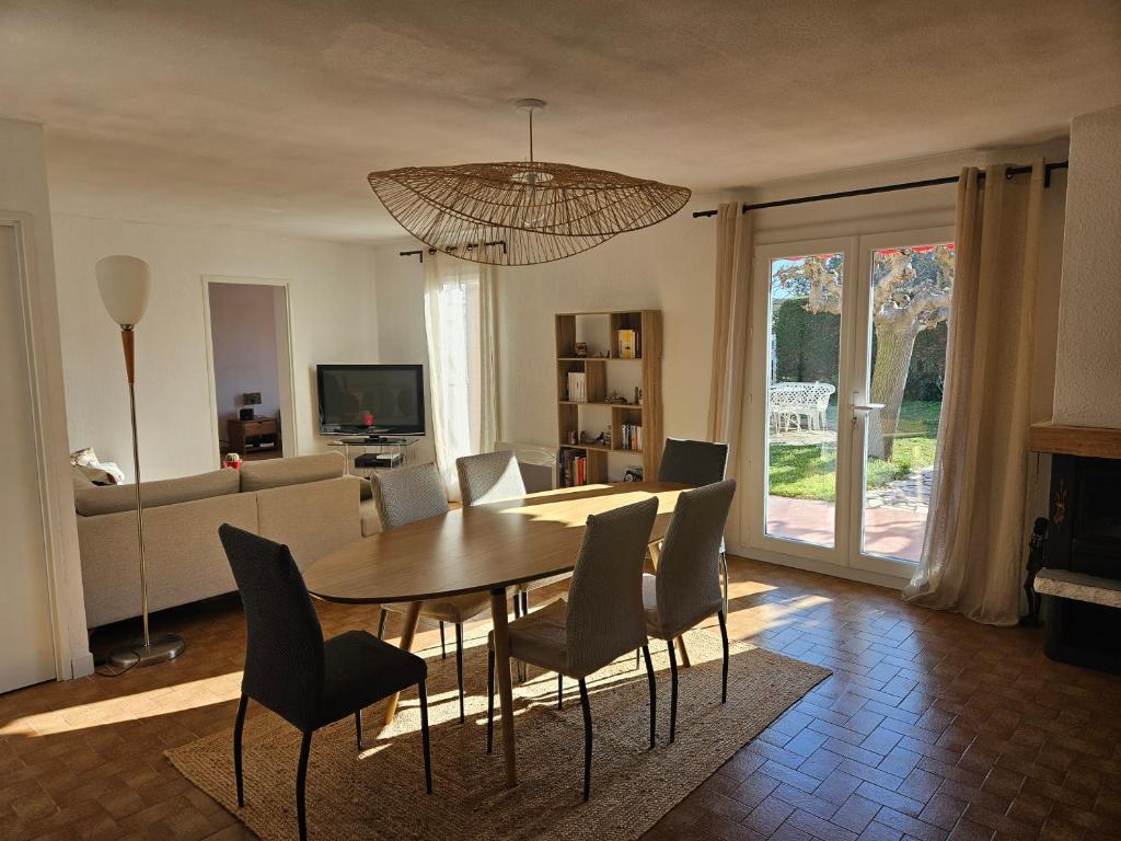 une table à manger et des chaises dans un salon dans l'établissement Maison de vacances avec jardin à 500 m de la plage, à Valras-Plage