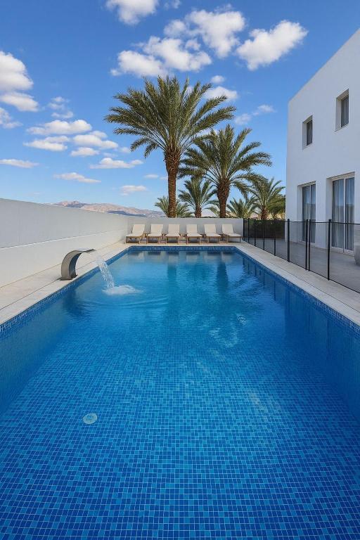 a large swimming pool with palm trees and a building at VILLA Leonard וילה לאונרד אילת in Eilat