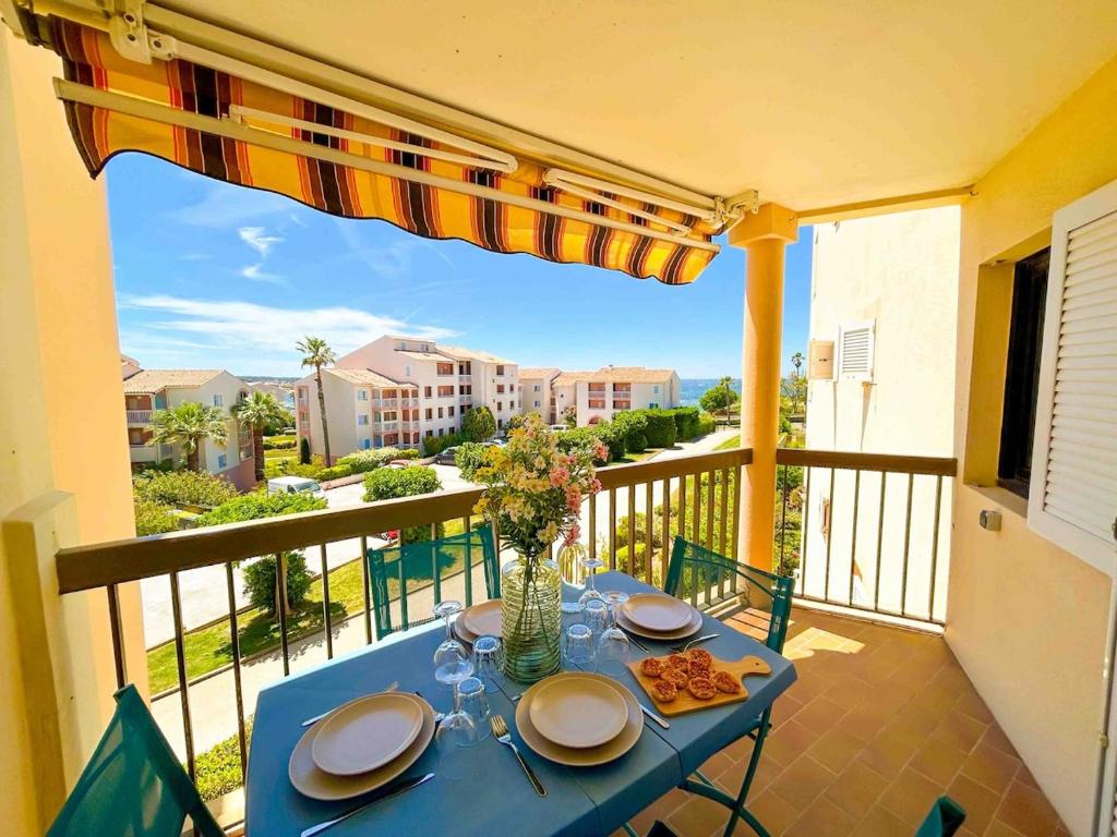 une table bleue avec des assiettes de nourriture sur un balcon dans l'établissement T2 au calme avec piscine et parking, à Six-Fours-les-Plages