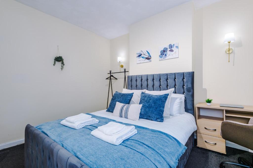 a bedroom with a blue and white bed with towels on it at Stylish & Delightful 3BD Family Home - Near Coop Live & Etihad Stadium - Free Parking - Unlimited high speed WiFi in Manchester