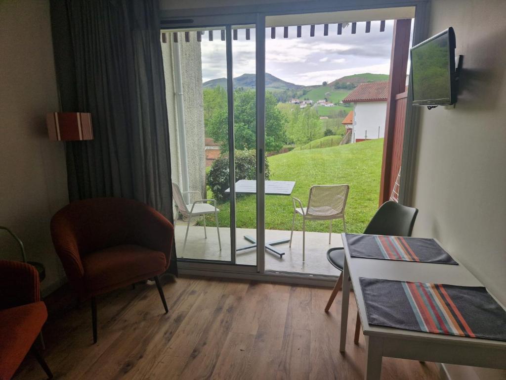 une pièce avec une table et des chaises et une grande fenêtre dans l'établissement BANCA Piscine Vue Montagnes, à Souraïde