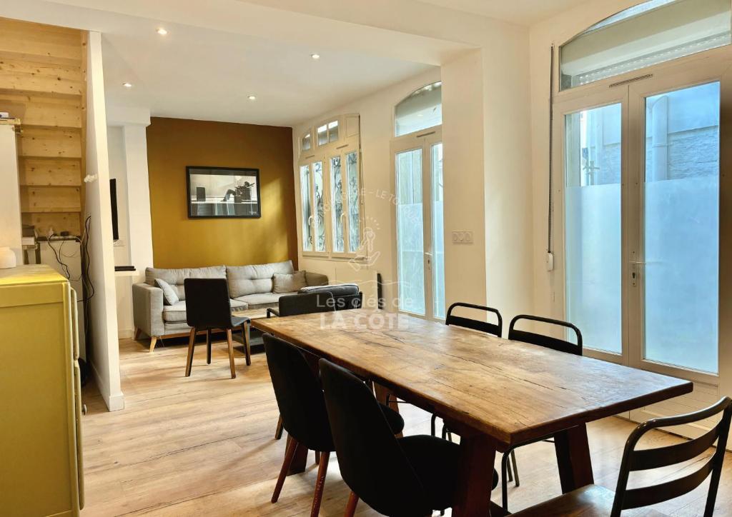 een eetkamer en een woonkamer met een houten tafel en stoelen bij Maison "Louisette" in Le Touquet-Paris-Plage