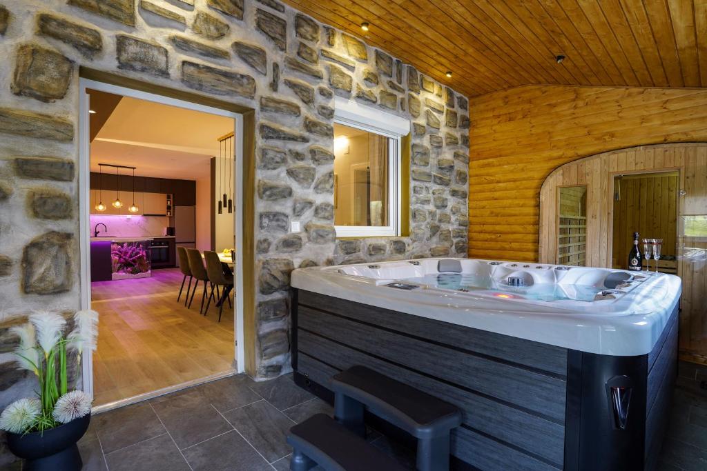 a large bathroom with a tub in a stone wall at Franjković Premium Suite with Private Jacuzzi & Sauna in Seliste Dreznicko