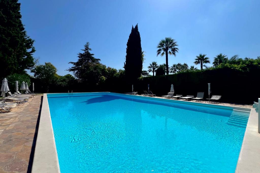 une piscine bleue avec des chaises et des palmiers dans l'établissement JUAN LES PINS 6 people pool tennis, à Juan-les-Pins