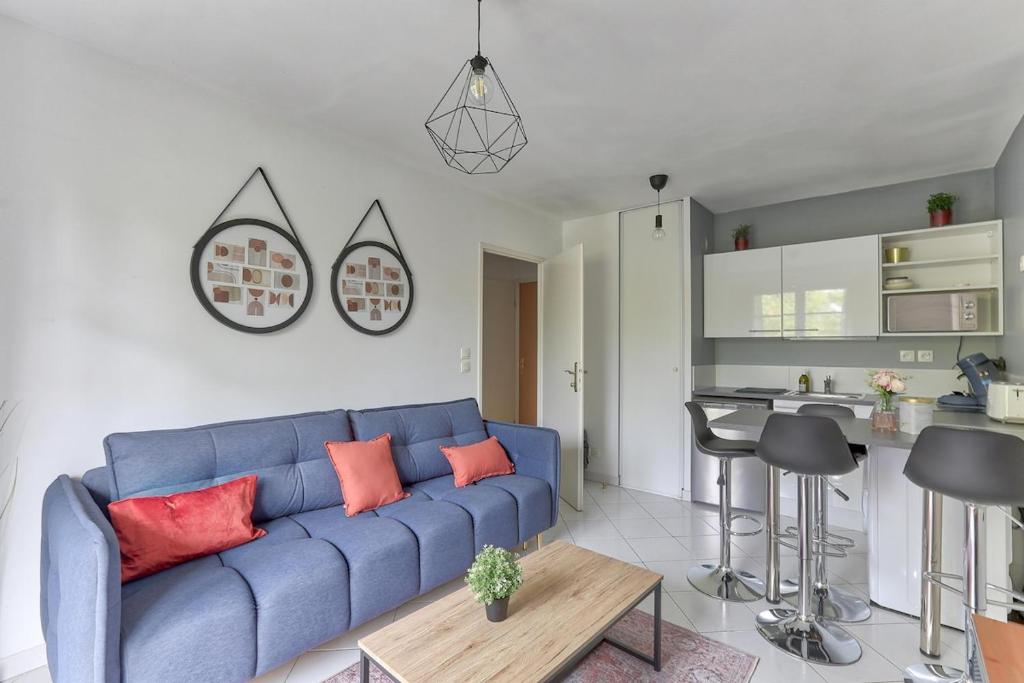 un salon avec un canapé bleu et une cuisine dans l'établissement Bel appartement au calme Paris Disney, à Bussy-Saint-Georges
