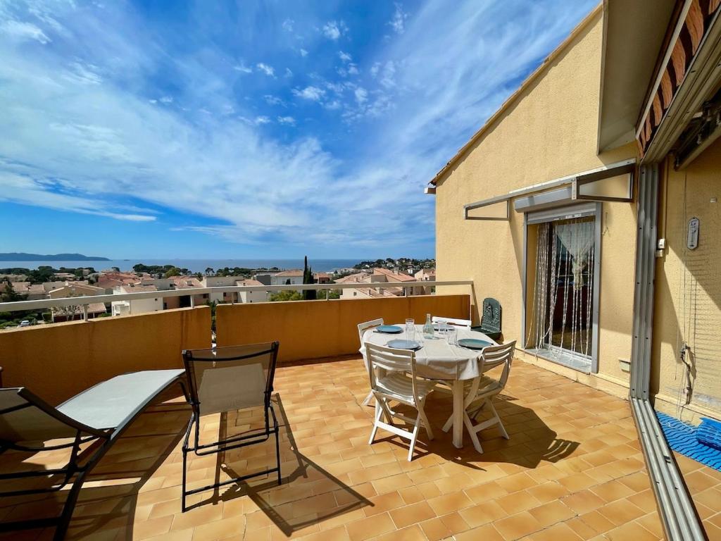 un patio avec une table et des chaises sur un balcon dans l'établissement Duplex - Piscine - Vue mer 180 degrès, à Carqueiranne
