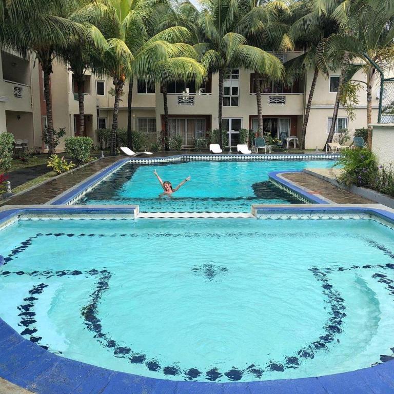 a person is swimming in a large swimming pool at Residence les orchidees D5 in Flic-en-Flac
