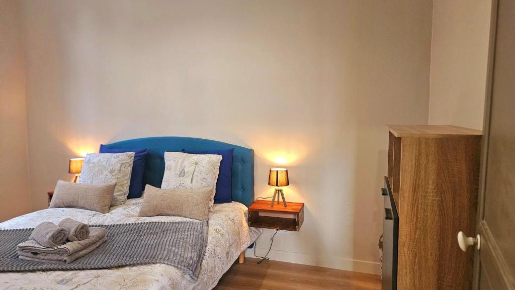 a bedroom with a bed with a blue head board at La Pause Dinannaise in Dinan