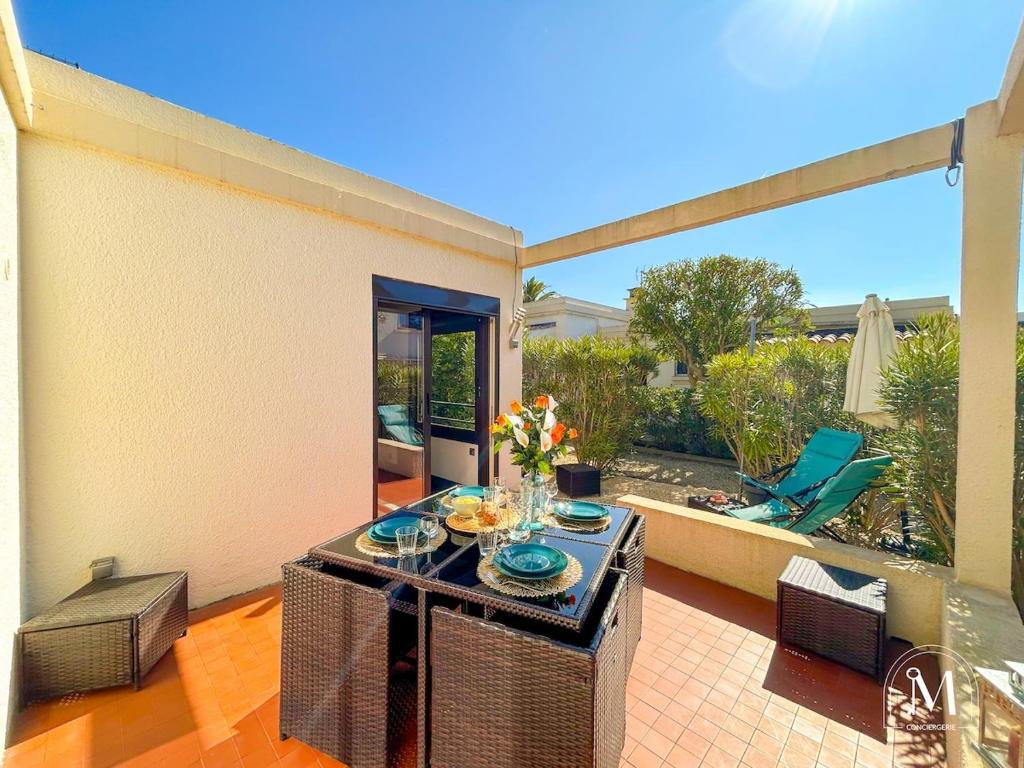d'une terrasse avec une table et des fleurs. dans l'établissement Rez-de-jardin à 1km du centre-ville de Six-Fours, à Six-Fours-les-Plages