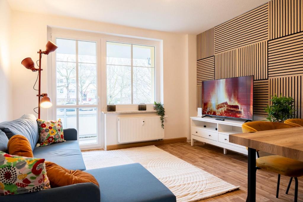 a living room with a blue couch and a flat screen tv at Atelierwohnung am Stadtpark in Chemnitz