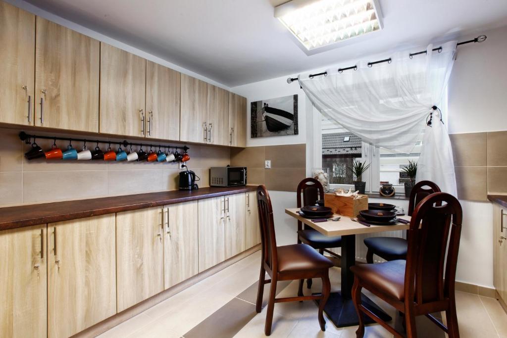 una cocina con armarios de madera y una mesa con sillas. en Sejf House, en Gdansk