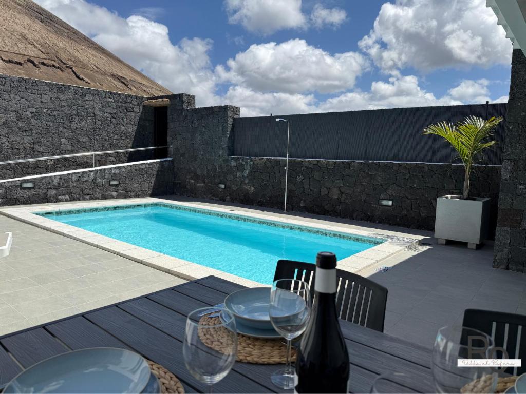 a table with a bottle of wine sitting next to a swimming pool at villa el rofero in Tinajo