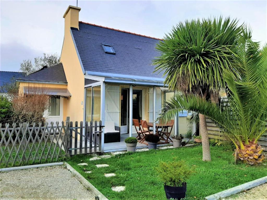 une maison avec une clôture et un palmier dans l'établissement Rigadell, à Penmarcʼh