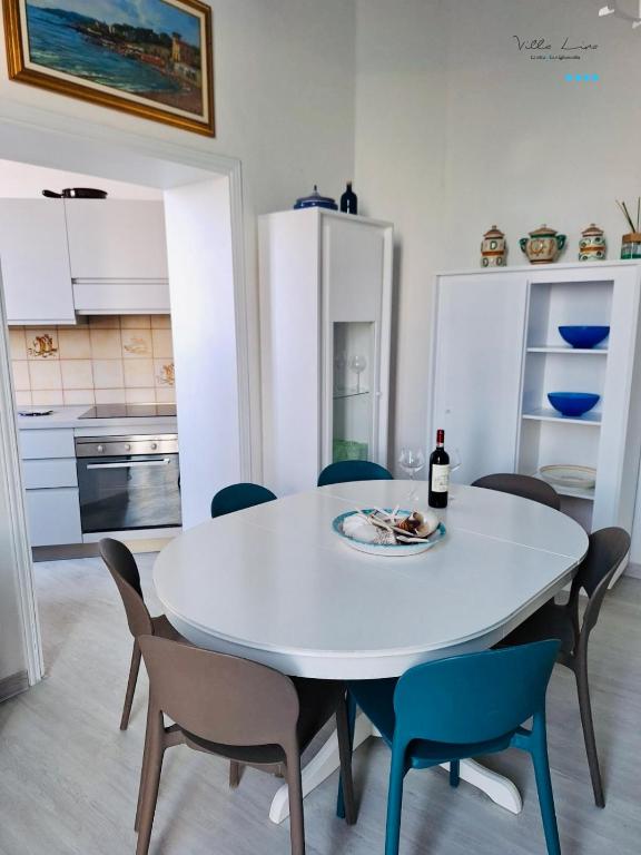 a white dining room table with chairs and a bottle of wine at Villa Lina in Castiglioncello