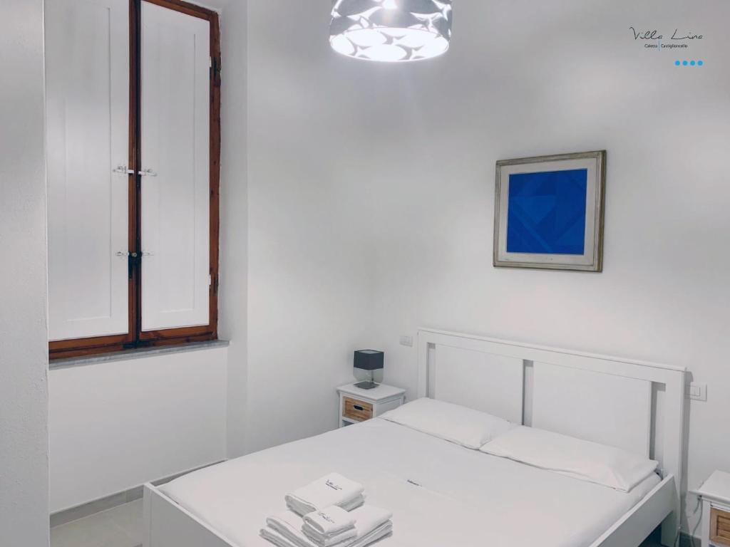a white room with a bed and a mirror at Villa Lina in Castiglioncello