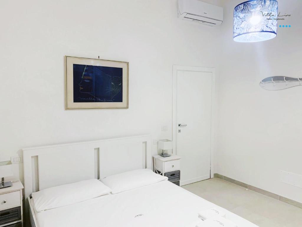 a white bedroom with a bed and a picture on the wall at Villa Lina in Castiglioncello