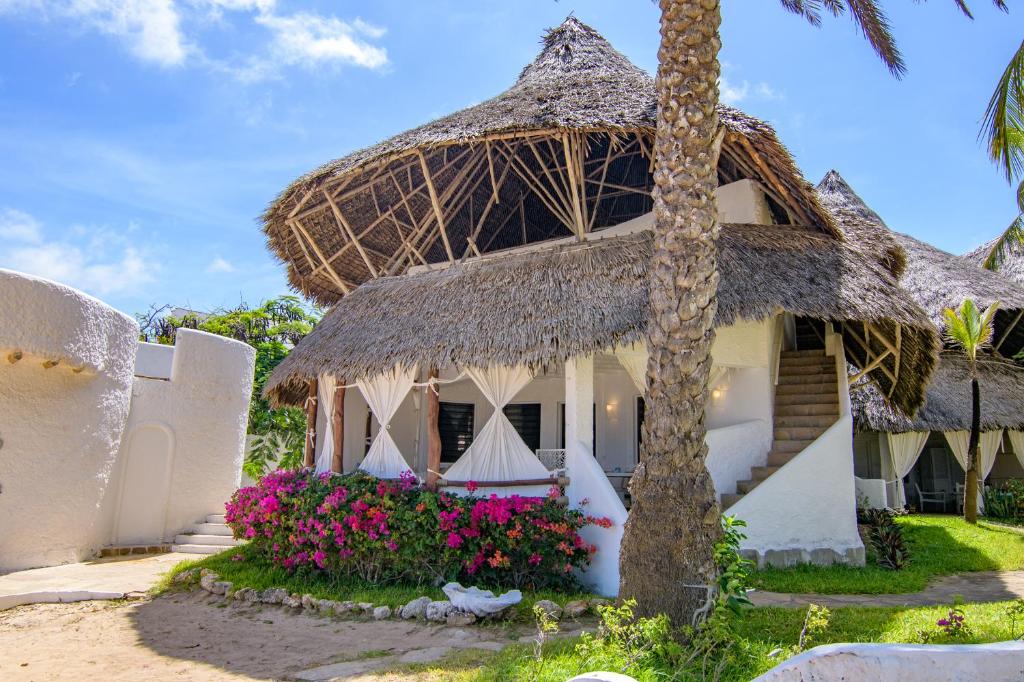 a villa with a thatched roof and flowers at Luxury Ocean Apartment - Malindi in Malindi