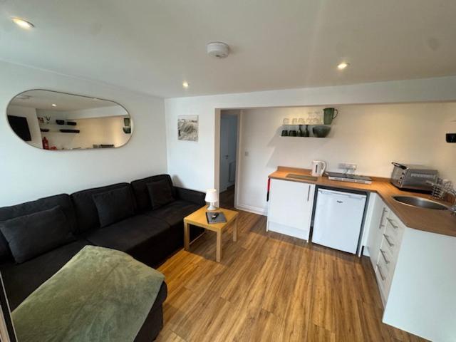 a living room with a black couch and a kitchen at Valletta House Holiday Apartments in Skegness