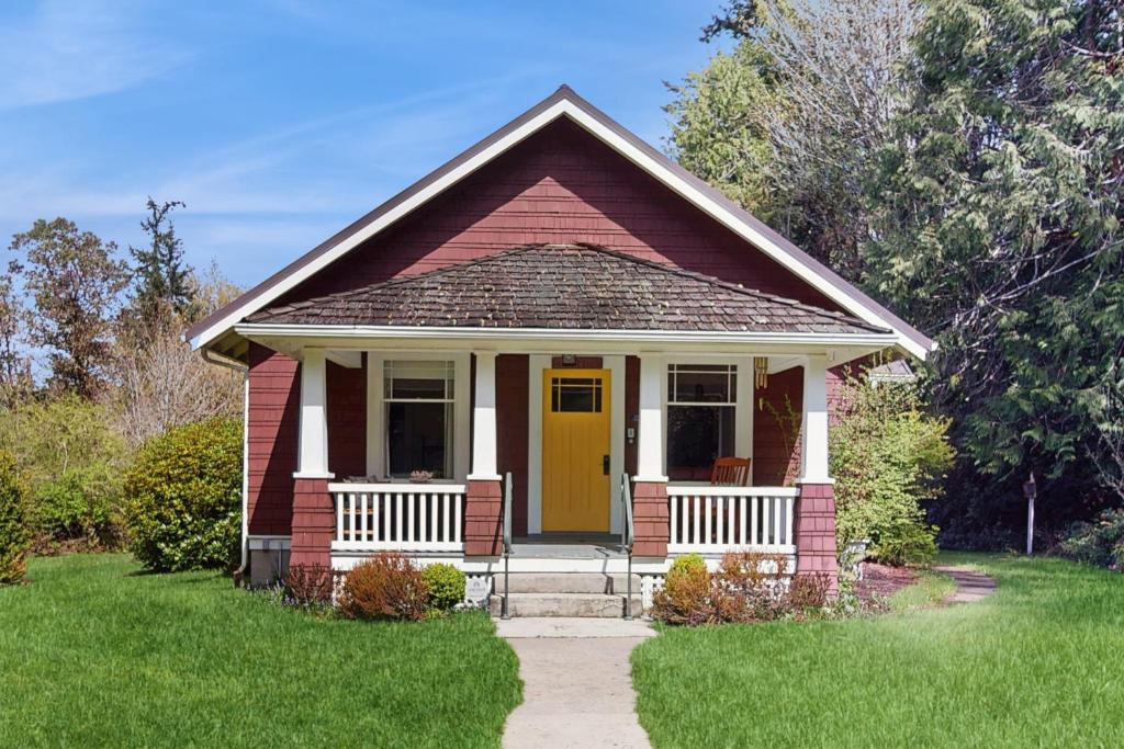 a small red house with a yellow door at Sunny Hill Farmhouse in Fort Ward