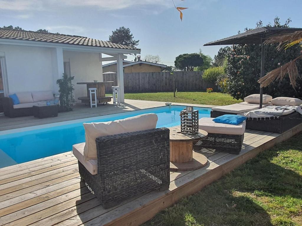 une cour arrière avec une piscine et une terrasse en bois dans l'établissement Villa Léonah Bassin d'Arcachon, à Gujan-Mestras