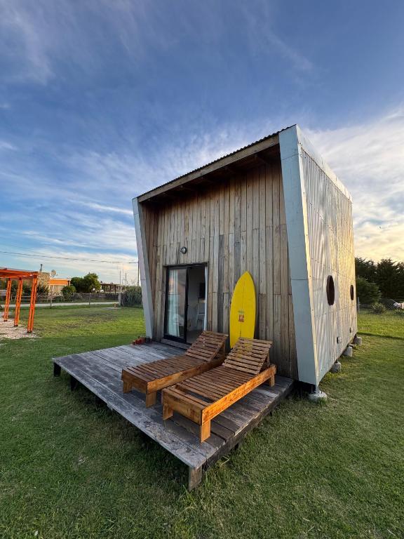 un petit bâtiment en bois avec bancs dans un champ dans l'établissement AMARRA Camet Norte, à Camet Norte