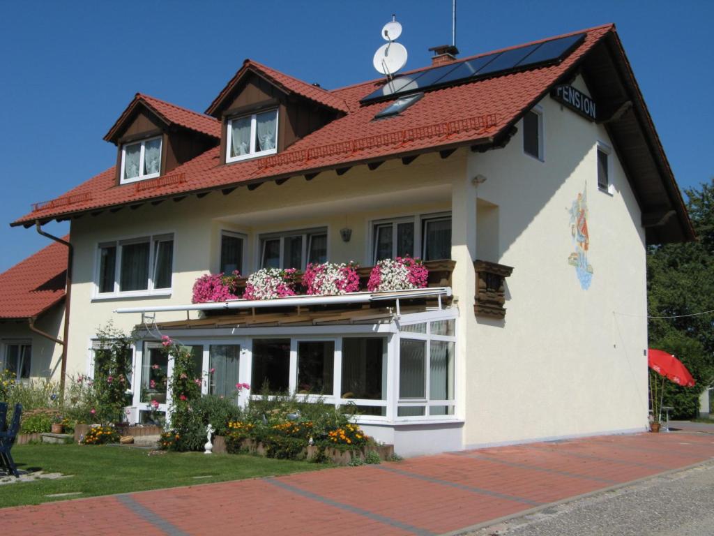 a house with a red roof and flowers on the balcony at Pension Wolkenstein in Langenbruck