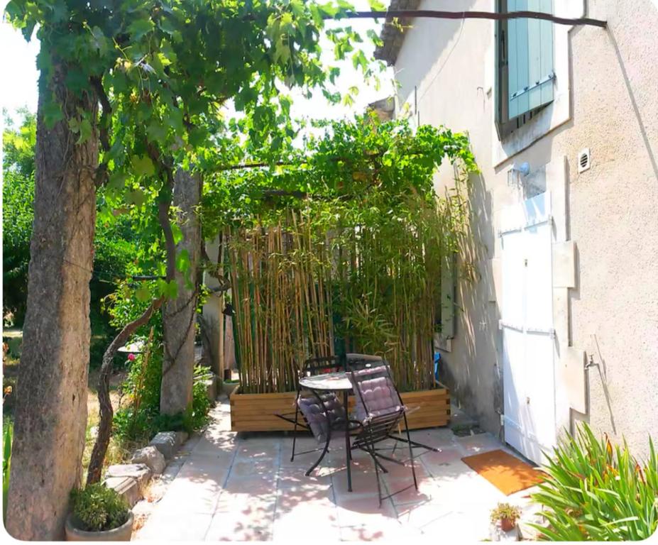 un patio avec une table et des chaises à côté d'un bâtiment dans l'établissement Maisonnée dans mas provençal typique, à Saint-Rémy-de-Provence