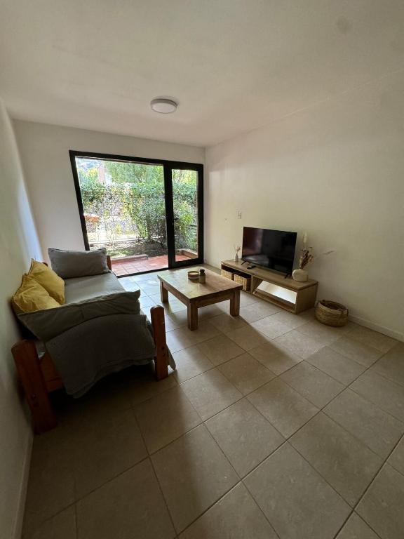 a living room with a couch and a tv at Jardines de Fosbery in San Martín de los Andes