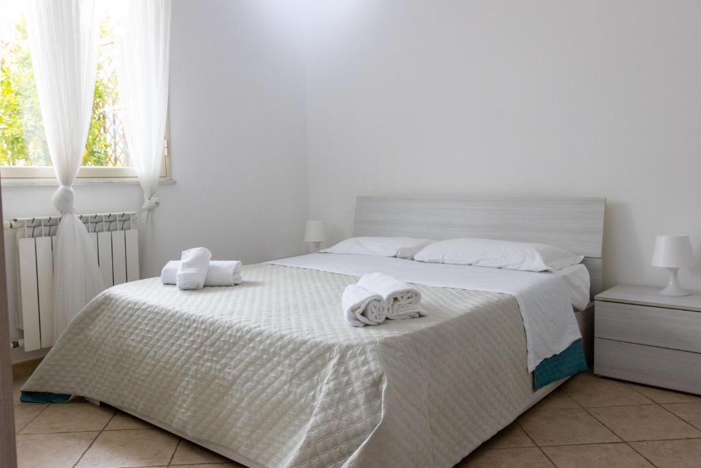 a white bedroom with a bed with towels on it at Andrea's Dépendance in Letojanni