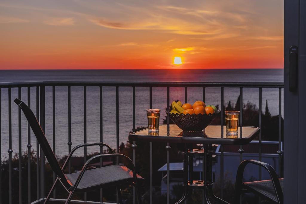 a table with a bowl of fruit on a balcony with the sunset at B&O Seaview in Bar