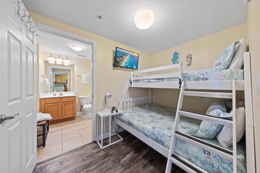 a bedroom with two bunk beds and a bathroom at 5 Star Resort 11th Fl Stunning Sunrise 2BR 2BA King Suite,Pools ,Shuttle or Walk to Beach in Destin