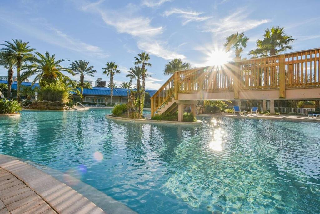 a swimming pool with palm trees and a bridge at 5 Star Resort 11th Fl Stunning Sunrise 2BR 2BA King Suite,Pools ,Shuttle or Walk to Beach in Destin