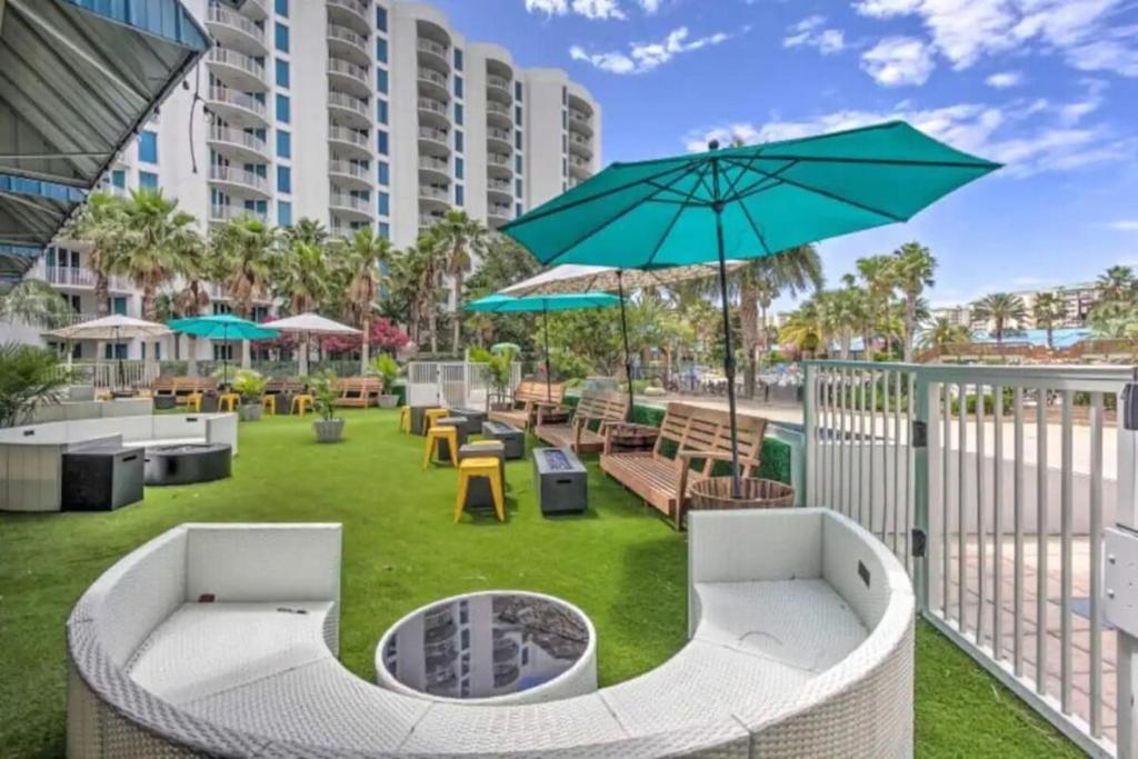 a patio with benches and tables and an umbrella at 5 Star Resort 11th Fl Stunning Sunrise 2BR 2BA King Suite,Pools ,Shuttle or Walk to Beach in Destin