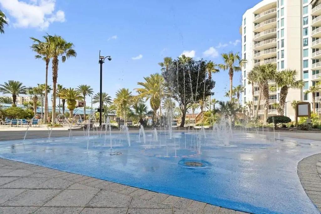 a fountain in a park with palm trees and buildings at 5 Star Resort 11th Fl Stunning Sunrise 2BR 2BA King Suite,Pools ,Shuttle or Walk to Beach in Destin