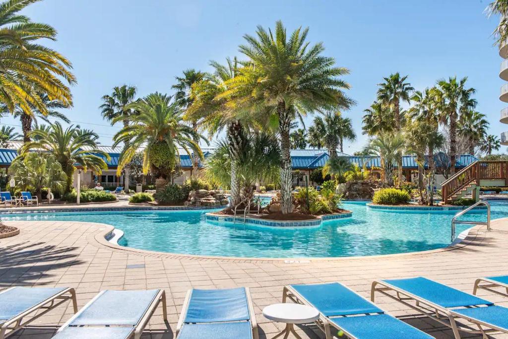 a large swimming pool with blue lounge chairs and palm trees at 5 Star Resort 11th Fl Stunning Sunrise 2BR 2BA King Suite,Pools ,Shuttle or Walk to Beach in Destin