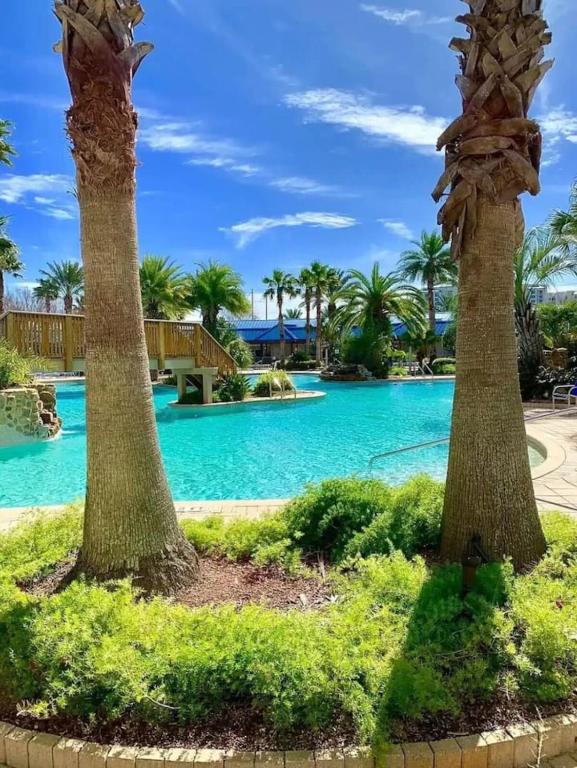 a pool with palm trees and blue water at 5 Star Resort 11th Fl Stunning Sunrise 2BR 2BA King Suite,Pools ,Shuttle or Walk to Beach in Destin