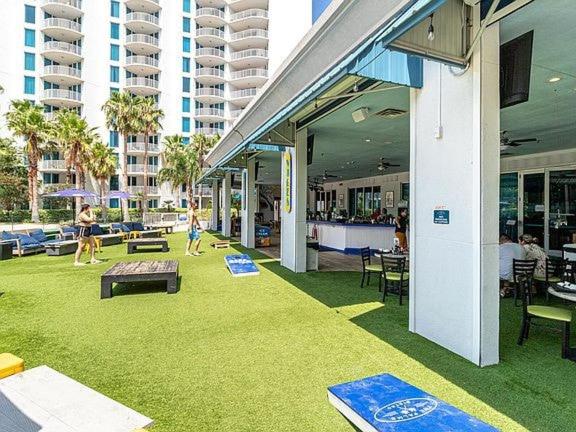 a building with a green yard with people playing frisbee at 5 Star Resort 11th Fl Stunning Sunrise 2BR 2BA King Suite,Pools ,Shuttle or Walk to Beach in Destin