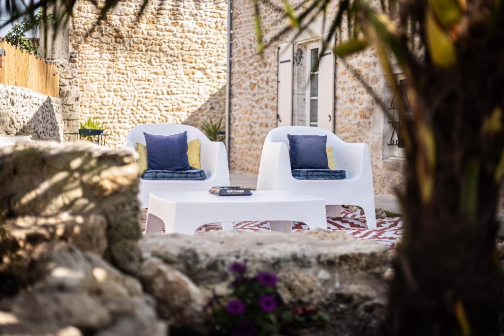 2 chaises blanches et une table avec des oreillers bleus dans l'établissement Le Logis de la Gabirotte, à Nieulle-sur-Seudre