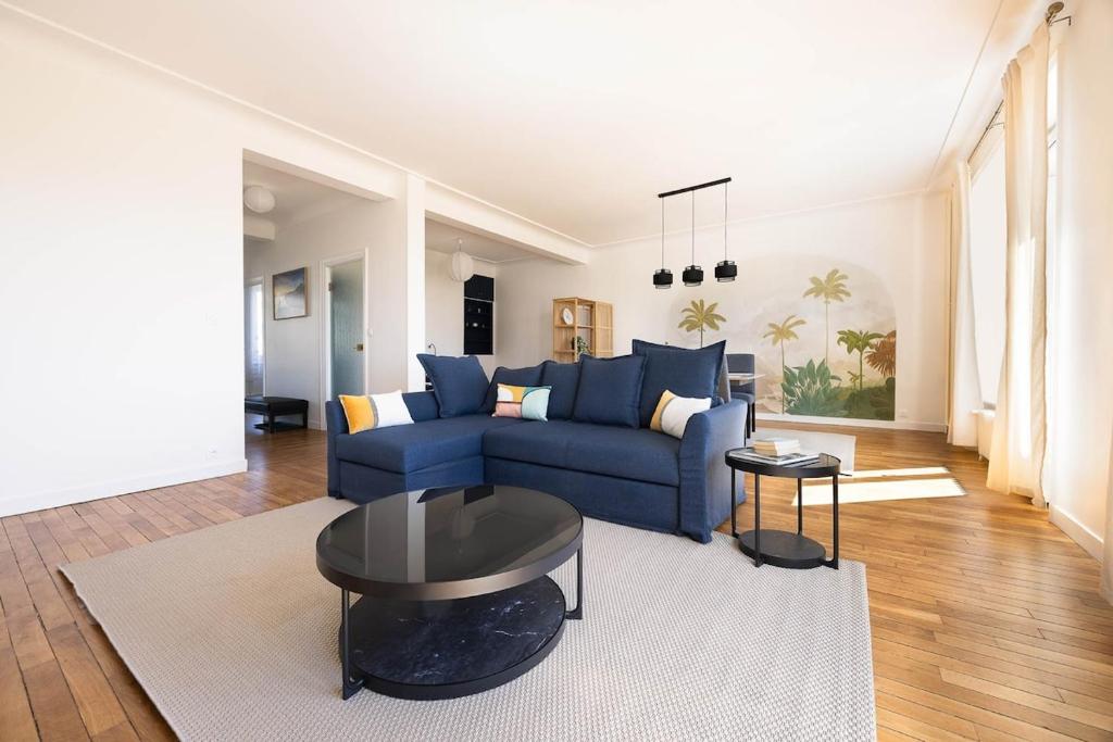un salon avec un canapé bleu et une table dans l'établissement Vue sur la place Wilson - Appt spacieux et lumineux, à Brest