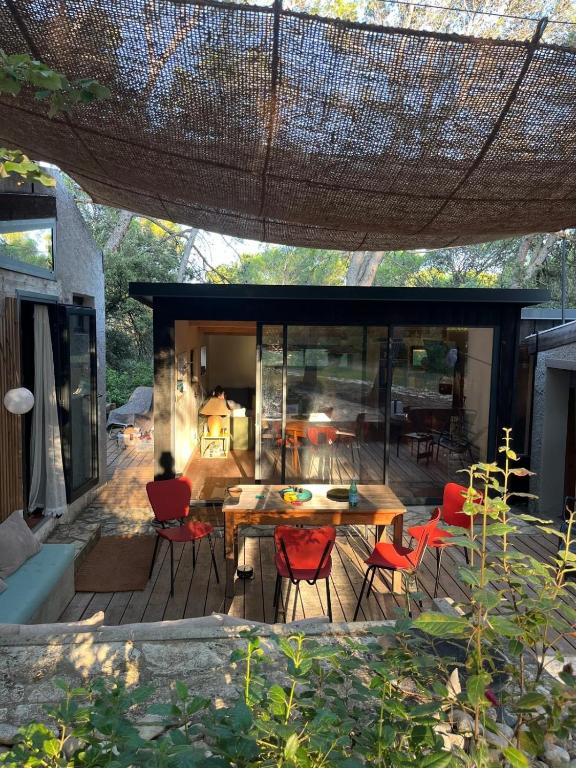 d'une terrasse avec une table en bois et des chaises rouges. dans l'établissement Villa avec patio et Pool House, à Saint-Nazaire