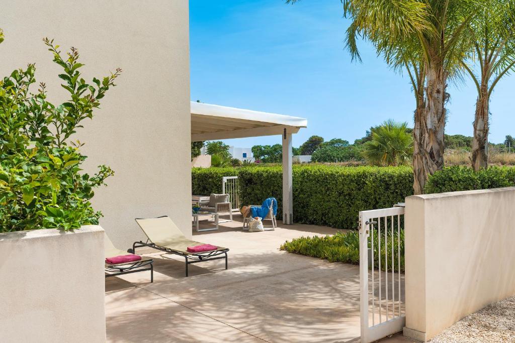 a patio with chairs and a porch with palm trees at Spuma di Mare - Riccio in San Vito lo Capo