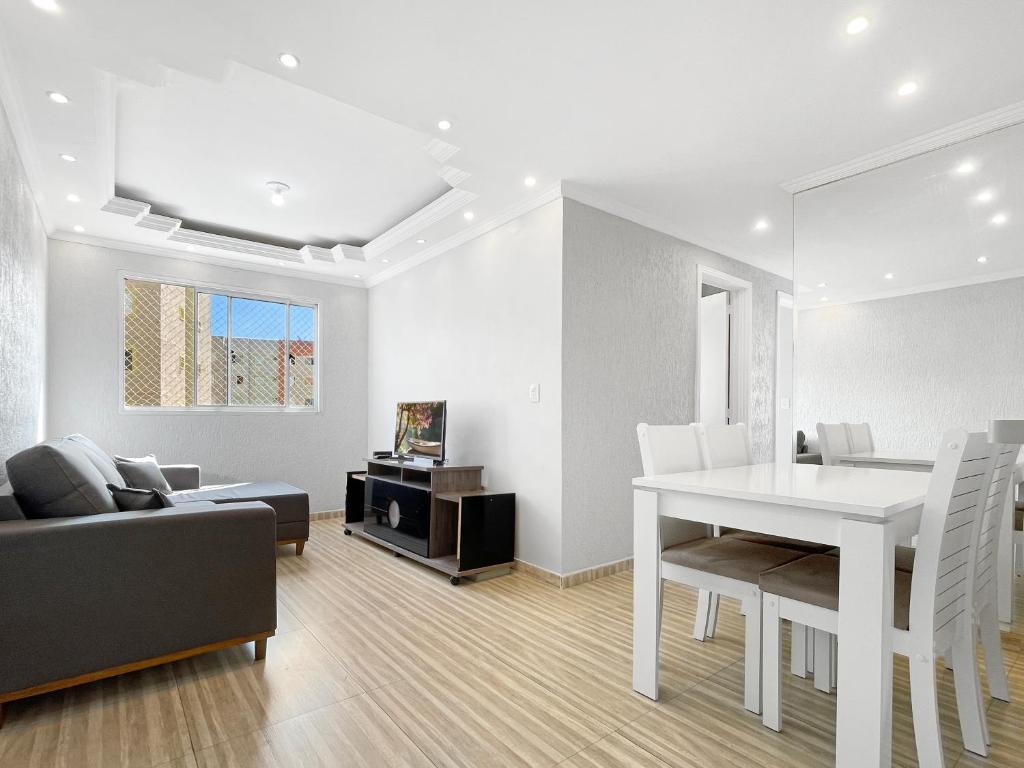 a white dining room with a white table and a couch at Plaza Shopping Barbecue Court 3 bedrooms in Carapicuíba