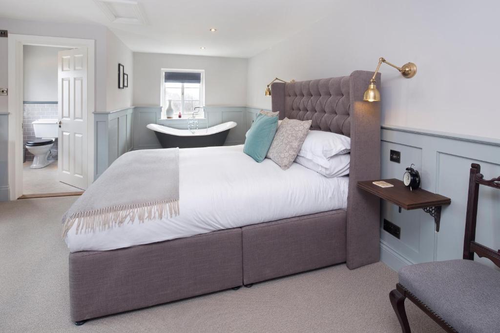 a bedroom with a large bed and a bathroom at The George Townhouse in Shipston-on-Stour